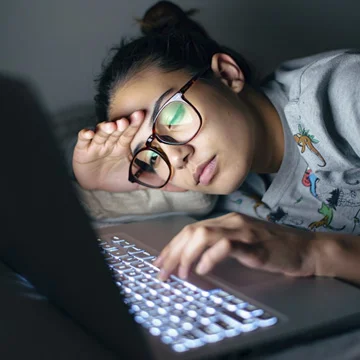 молодая девушка засыпает за экраном ноутбука