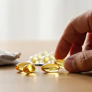 Рука берет желтую капсулу